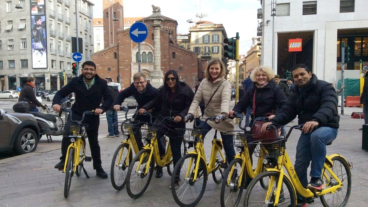 A team on rental bikes in a Milan street during a team building activity