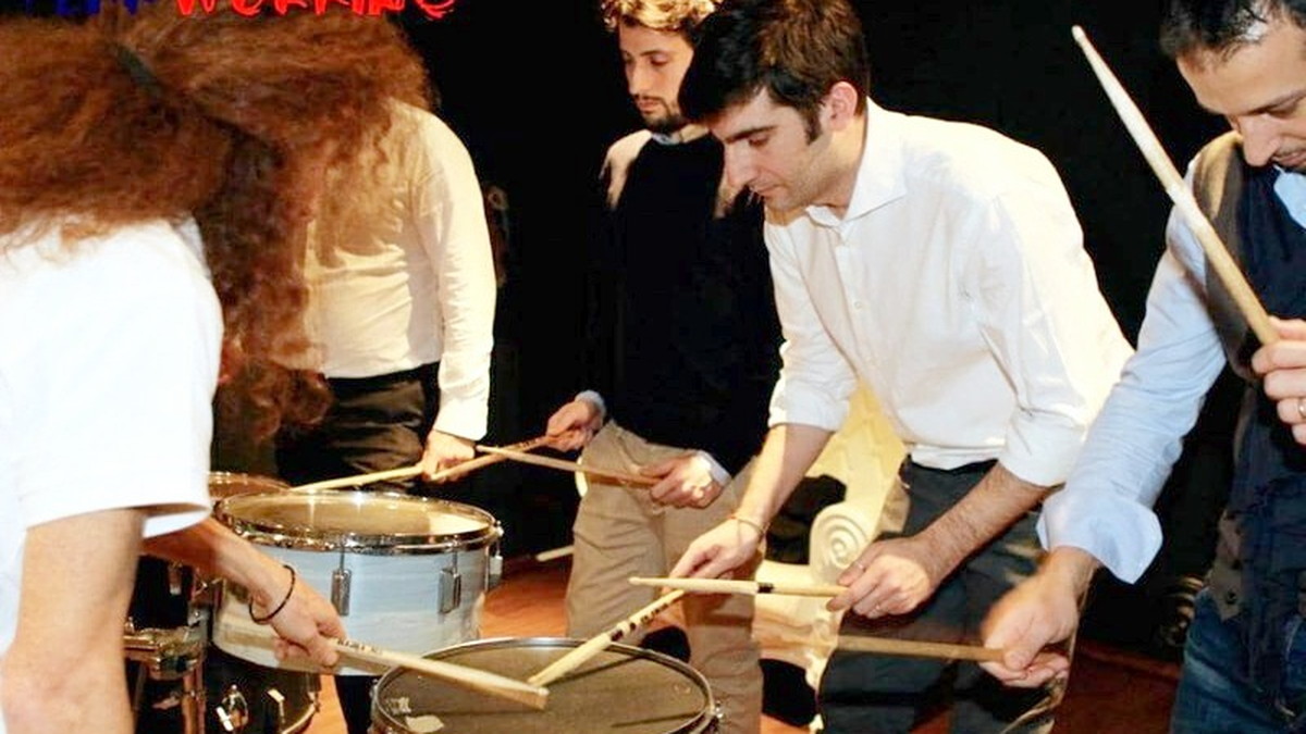 Mani e bacchette su rullanti e tamburi durante una sessione di percussioni