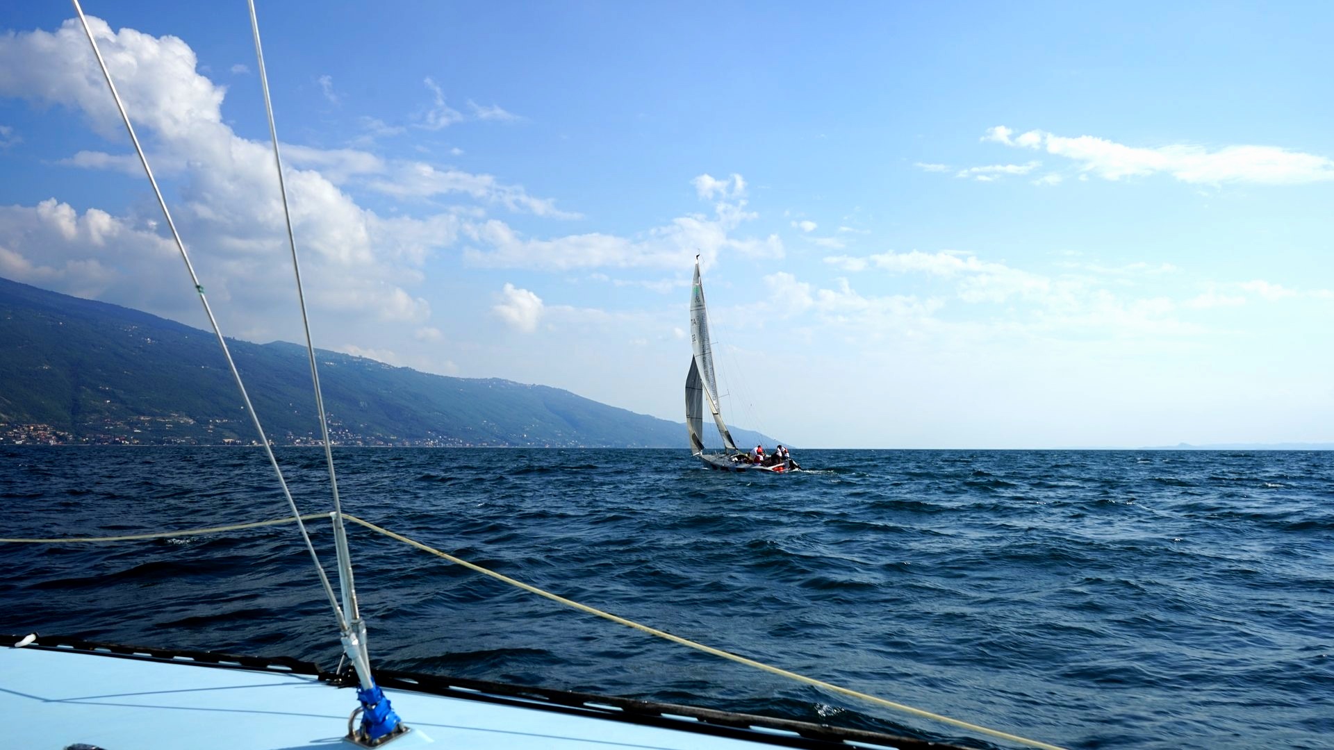Il ponte di una barca a vela con un'altra barca all'orizzonte sul lago