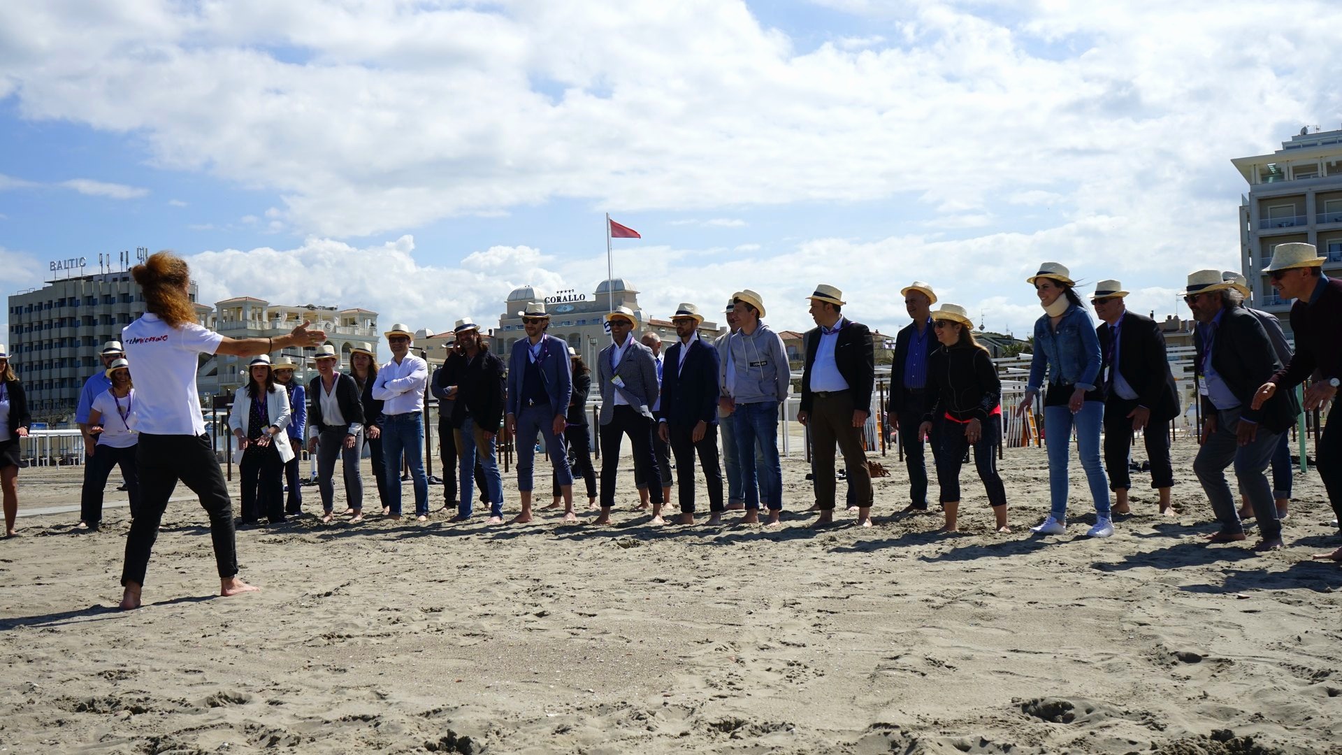 Un centinaio di partecipanti schierati sulla spiaggia durante una sessione di body percussion