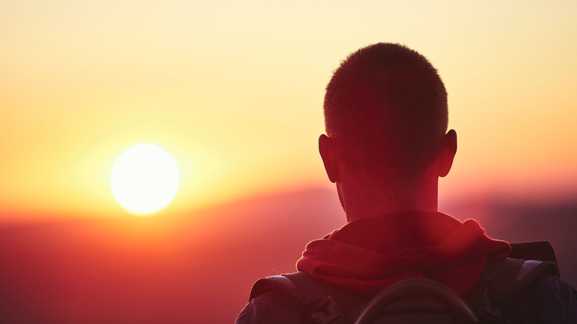 Escursionista di spalle davanti al sole che tramonta