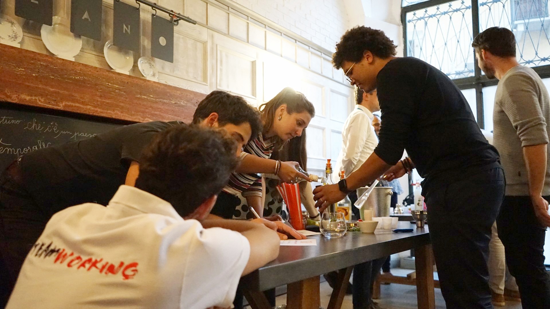 Partecipanti preparano cocktail dietro il bancone di un locale