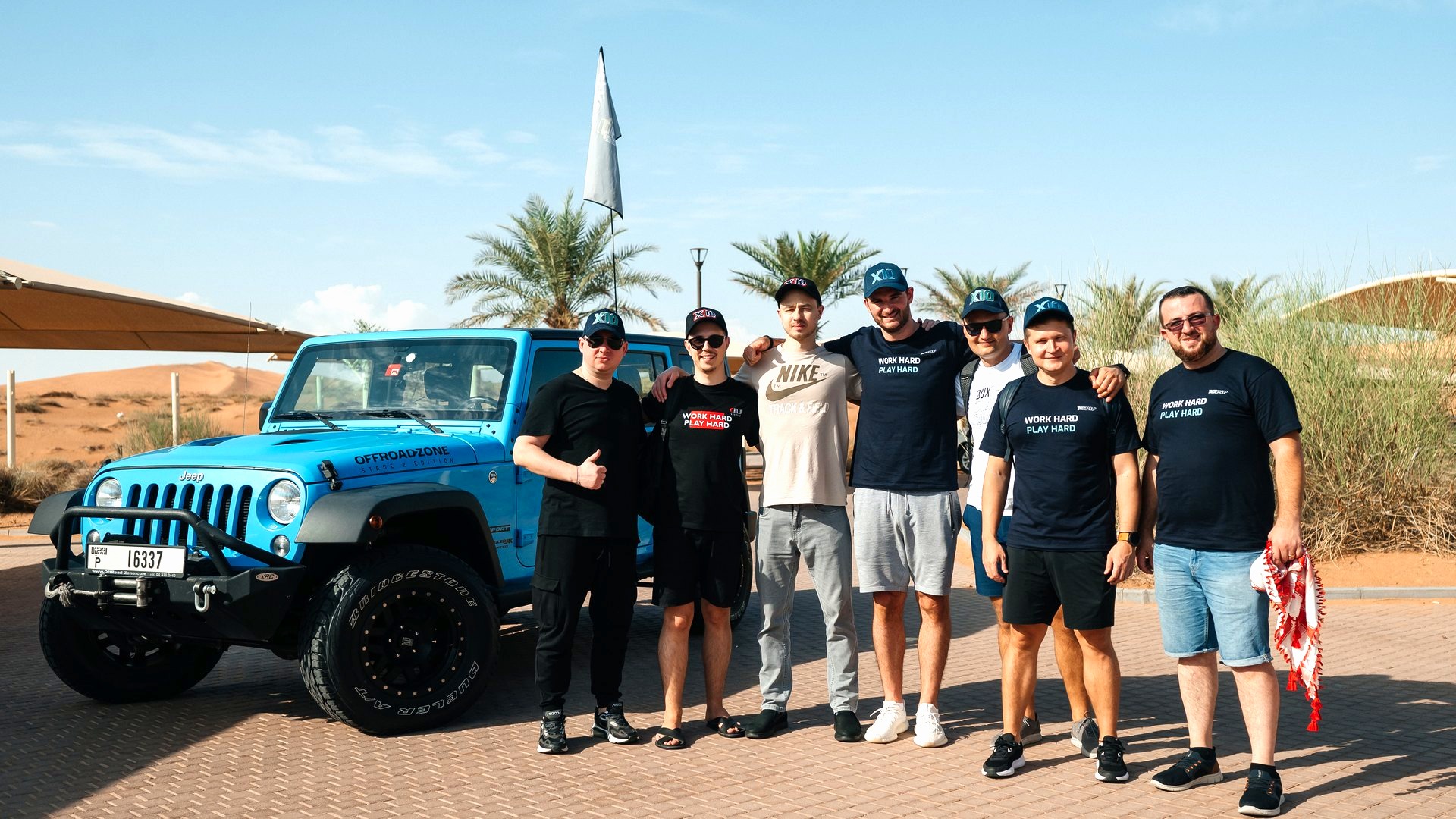 Squadra in maglia nera davanti a un fuoristrada fra le dune del deserto