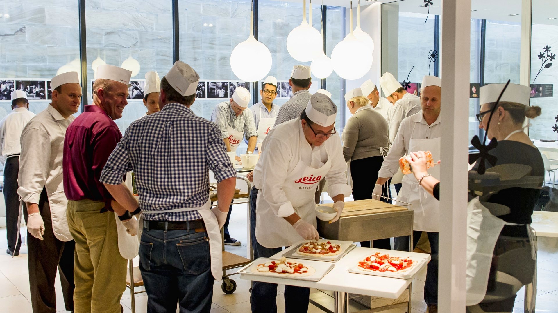 Sala luminosa con tutte le postazioni di cucina al lavoro durante un cooking team building