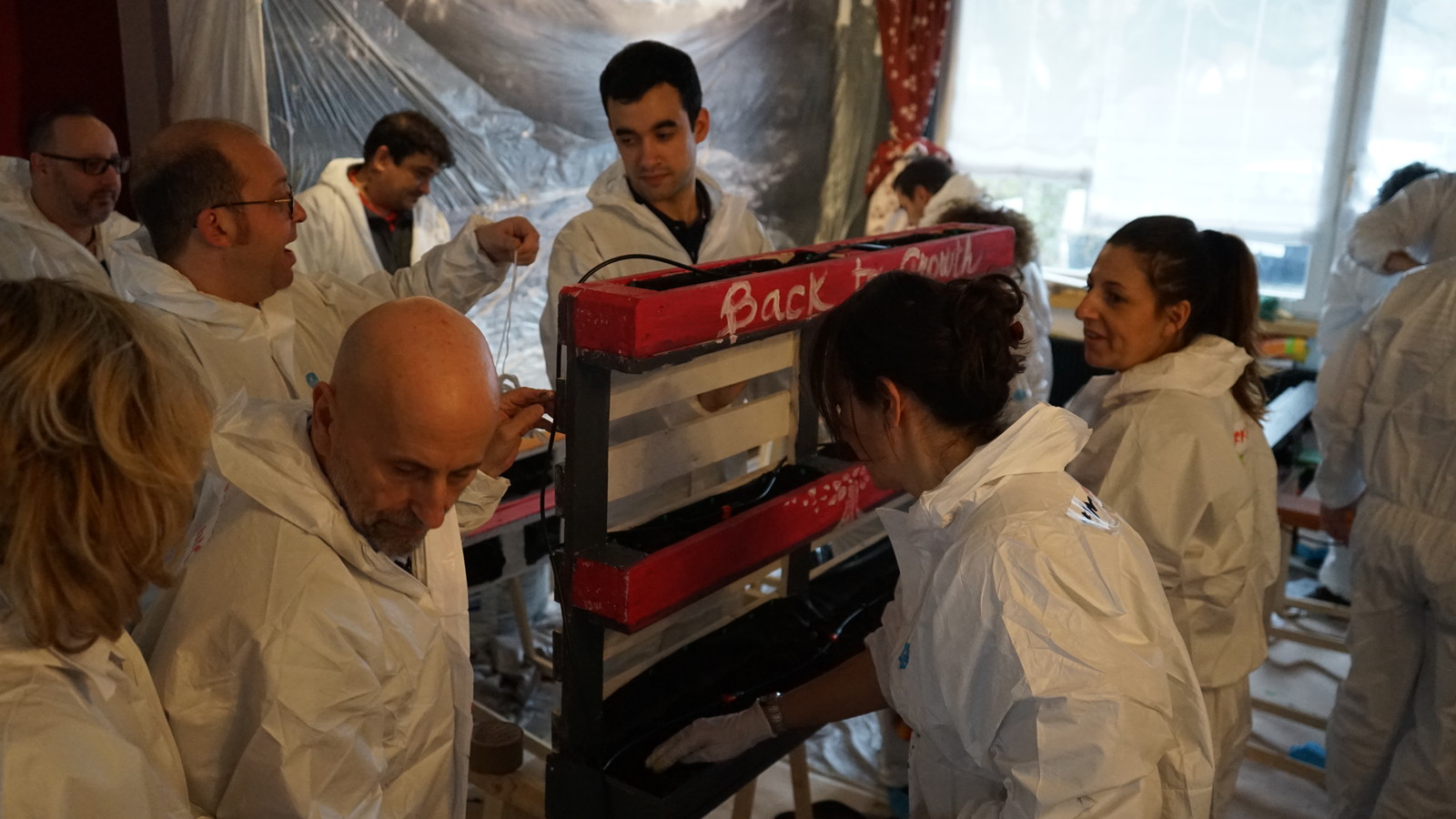 Il team in tuta da lavoro attorno alla parete verde appena costruita e dipinta