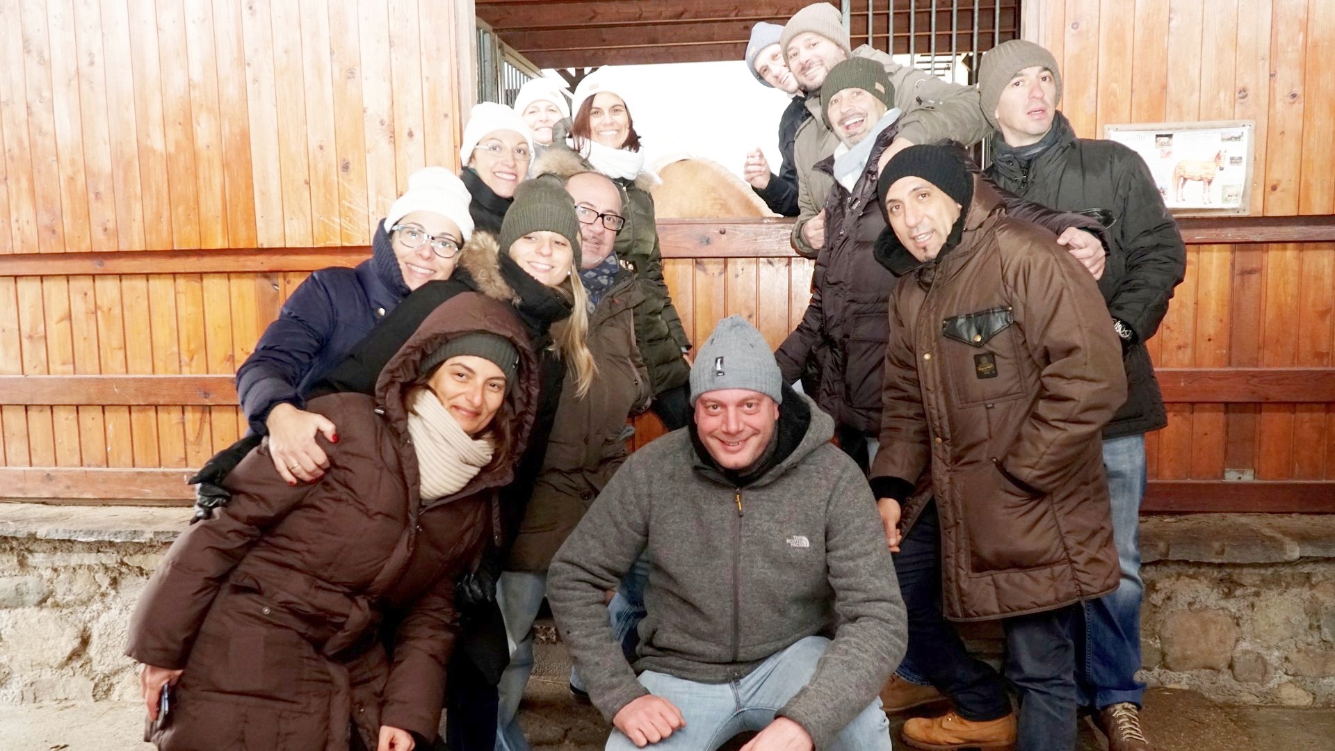 Gruppo di partecipanti nella stalla di una fattoria didattica insieme agli animali