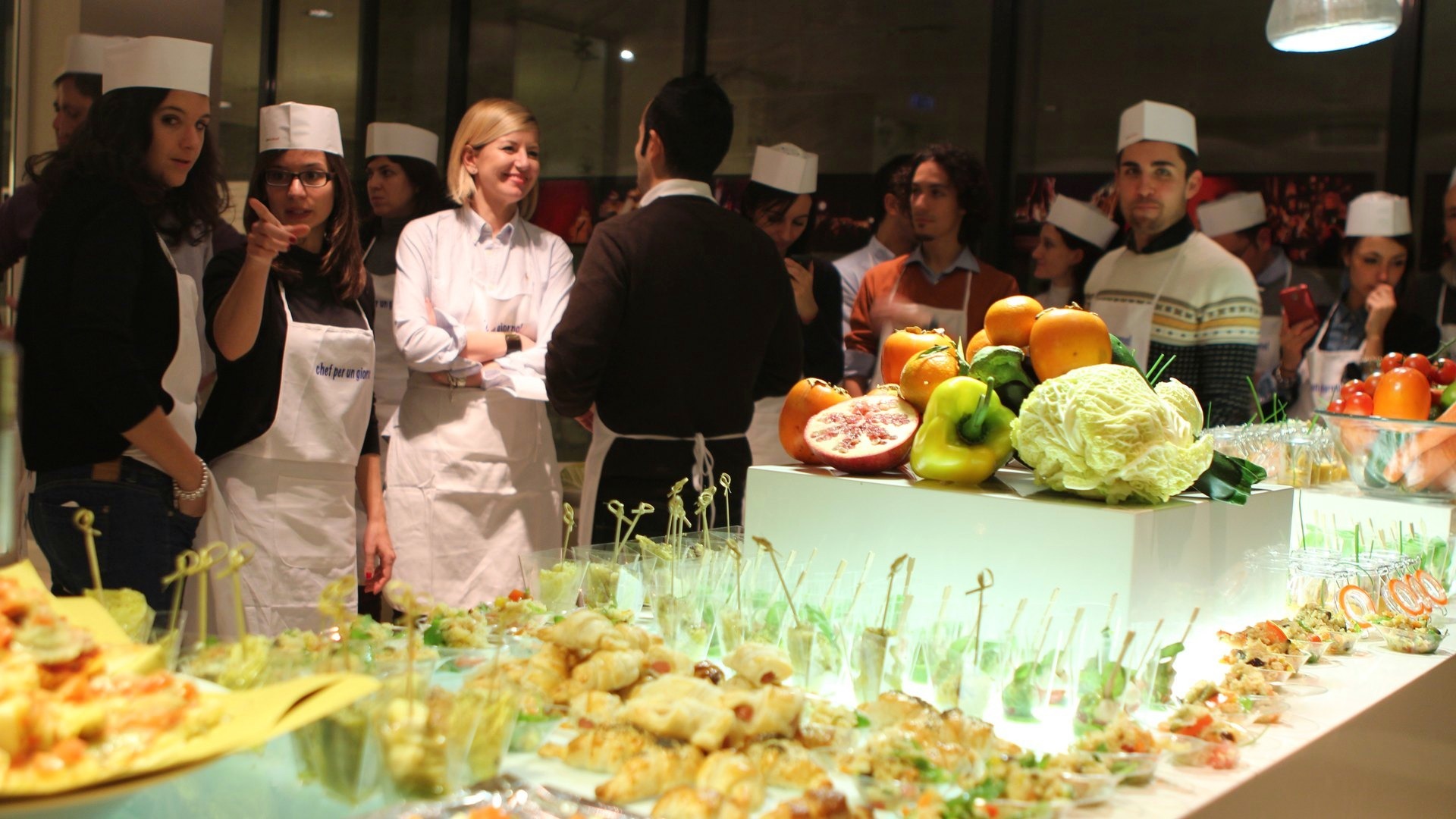 Partecipanti in toque dietro al banco con i finger food preparati