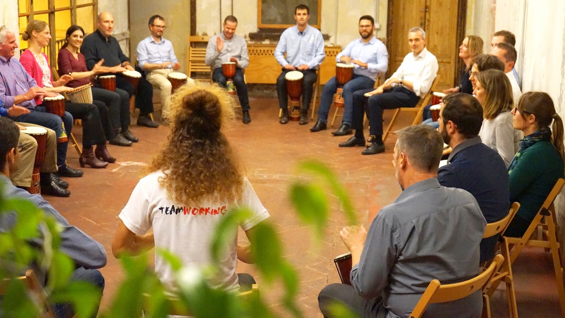 Cerchio di partecipanti con i tamburi durante un laboratorio di orchestra aziendale