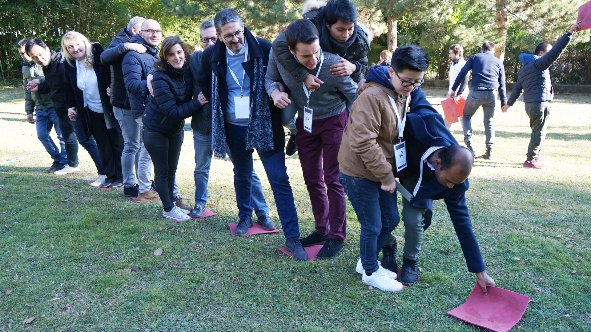 Fila di partecipanti su un prato che si passano un telo durante un'attivita' outdoor