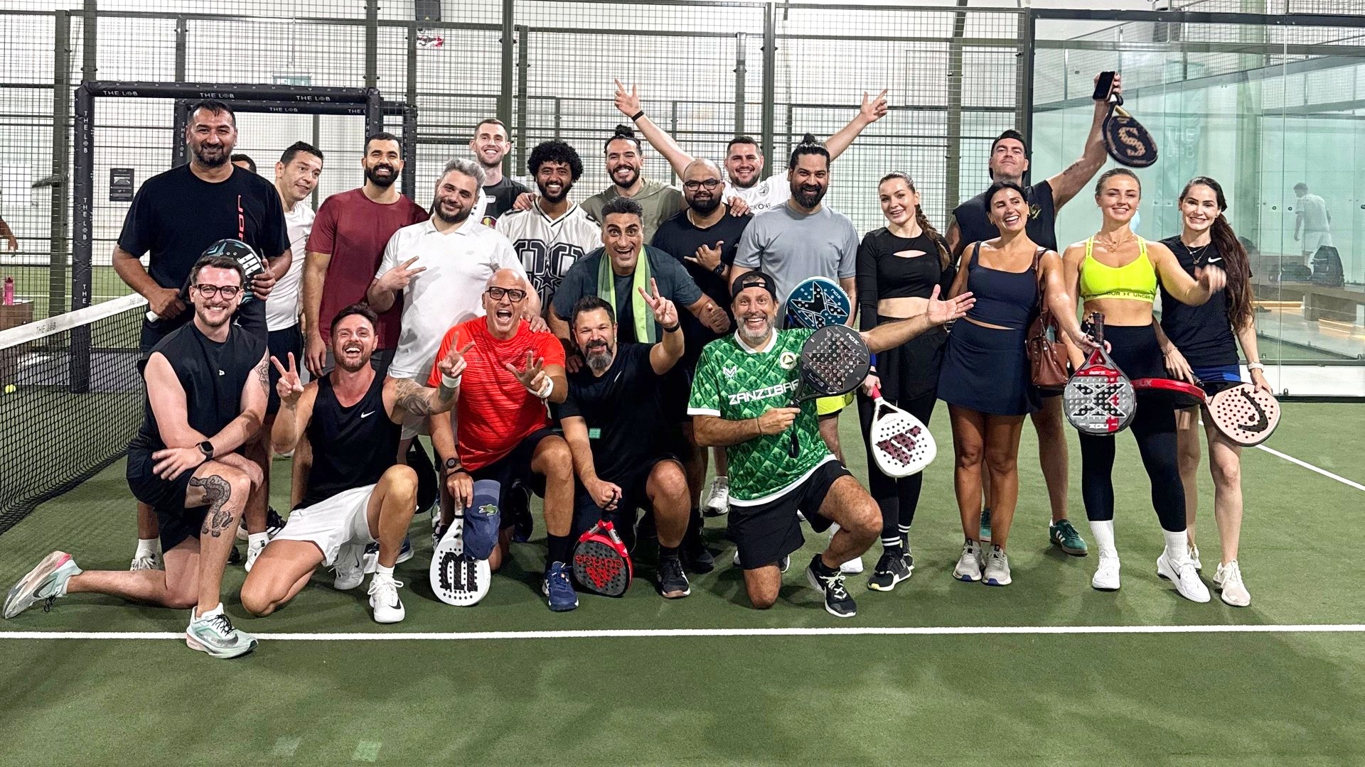 Il gruppo al completo su un campo da padel indoor, con le racchette in mano
