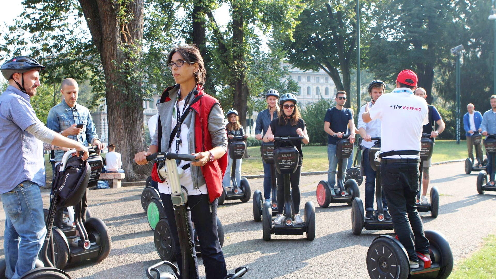 Fila di partecipanti in segway lungo un viale alberato con la guida davanti