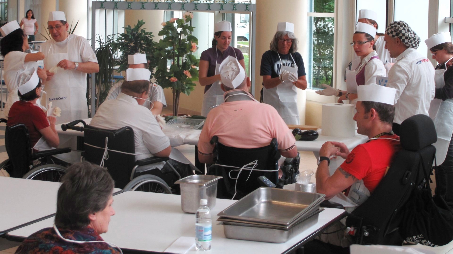 Partecipanti in toque ai tavoli durante un cooking solidale