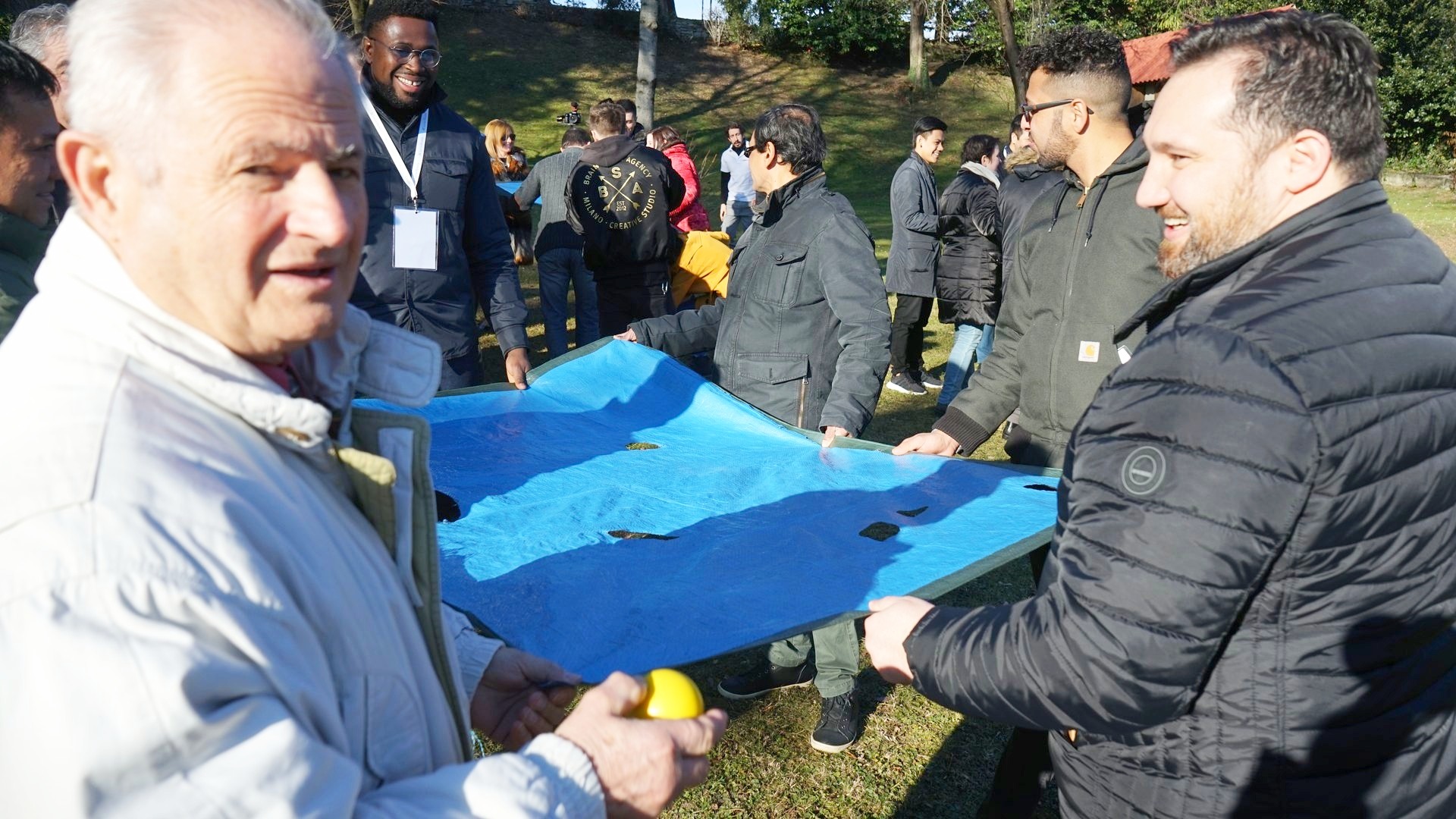 Due partecipanti reggono un telo durante un classico esercizio di outdoor training