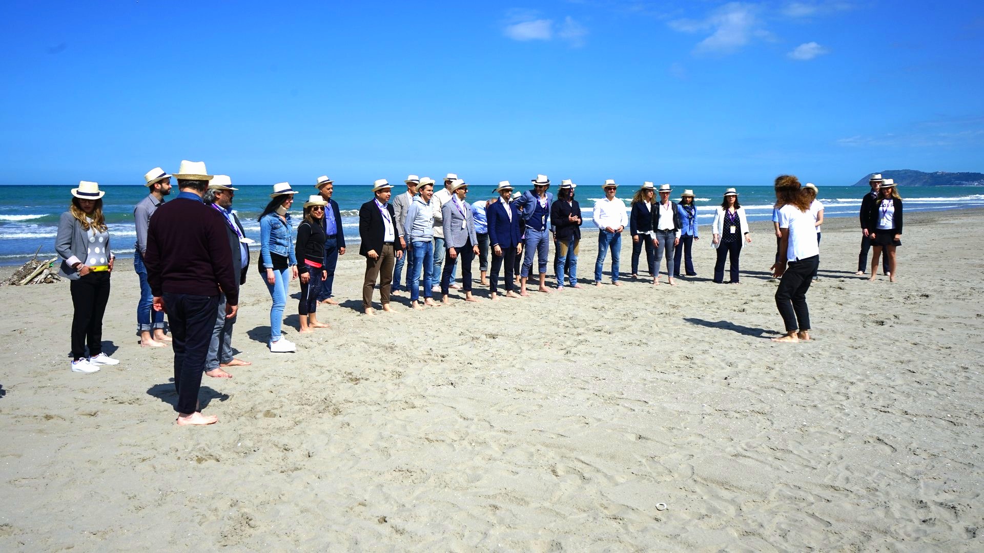 Lunga fila di partecipanti sulla spiaggia batte le mani a tempo durante un'attivita' di gruppo