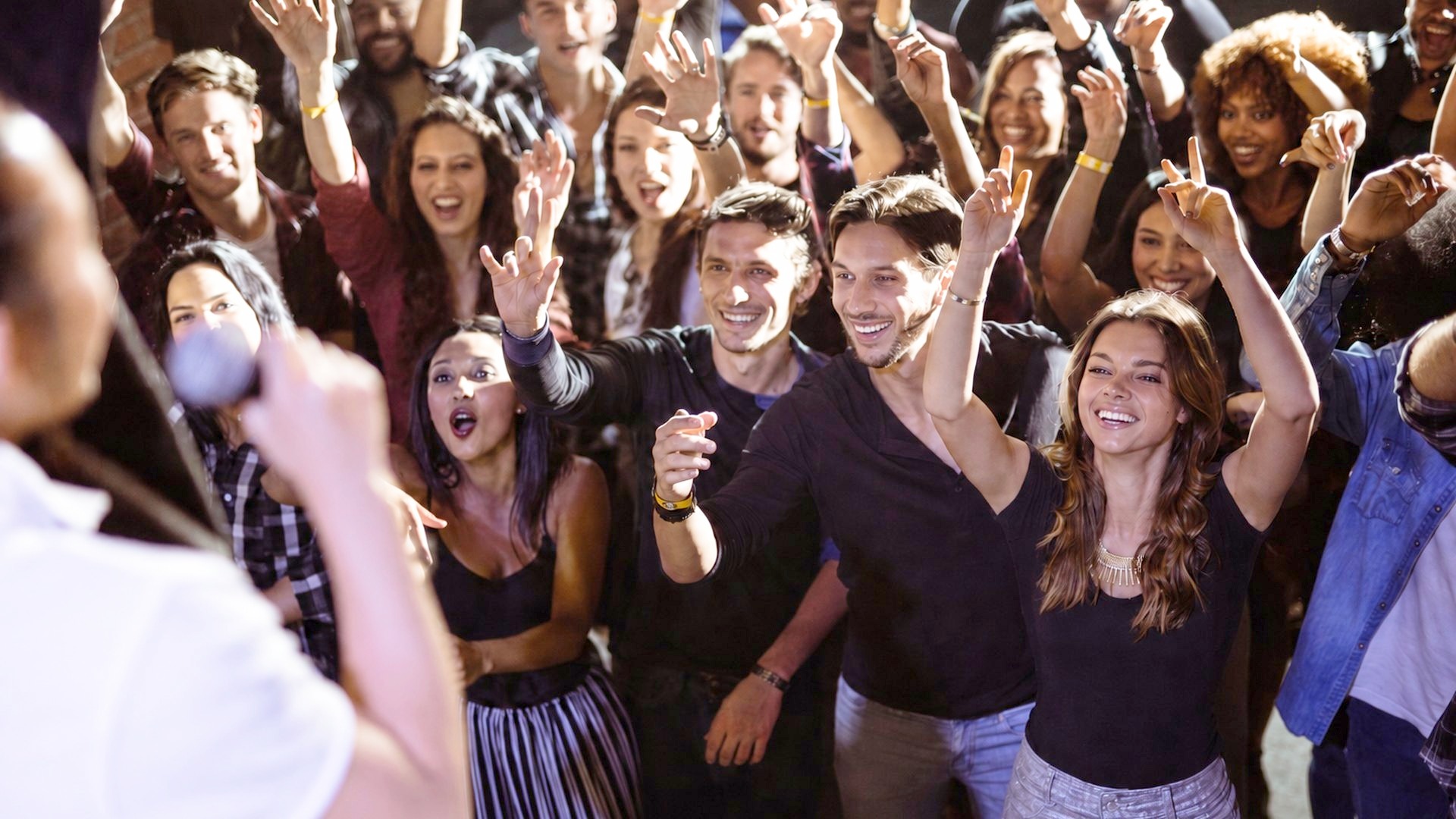 Folla di persone che ride e alza le braccia
