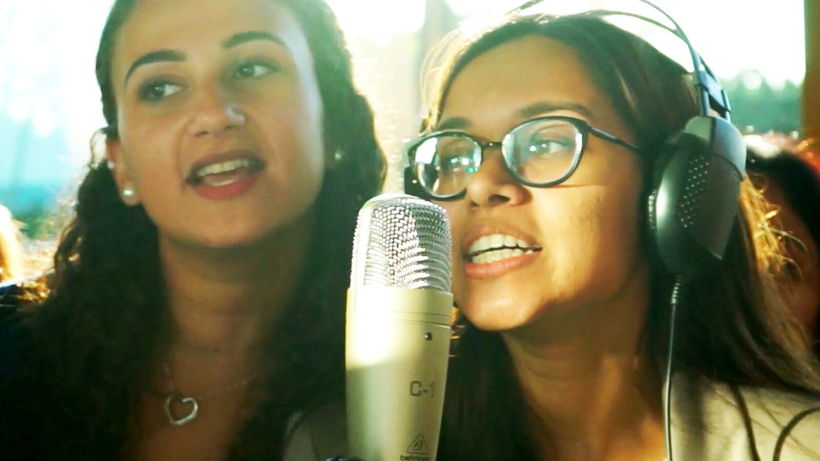 Due partecipanti cantano al microfono durante la registrazione del Corporate Song