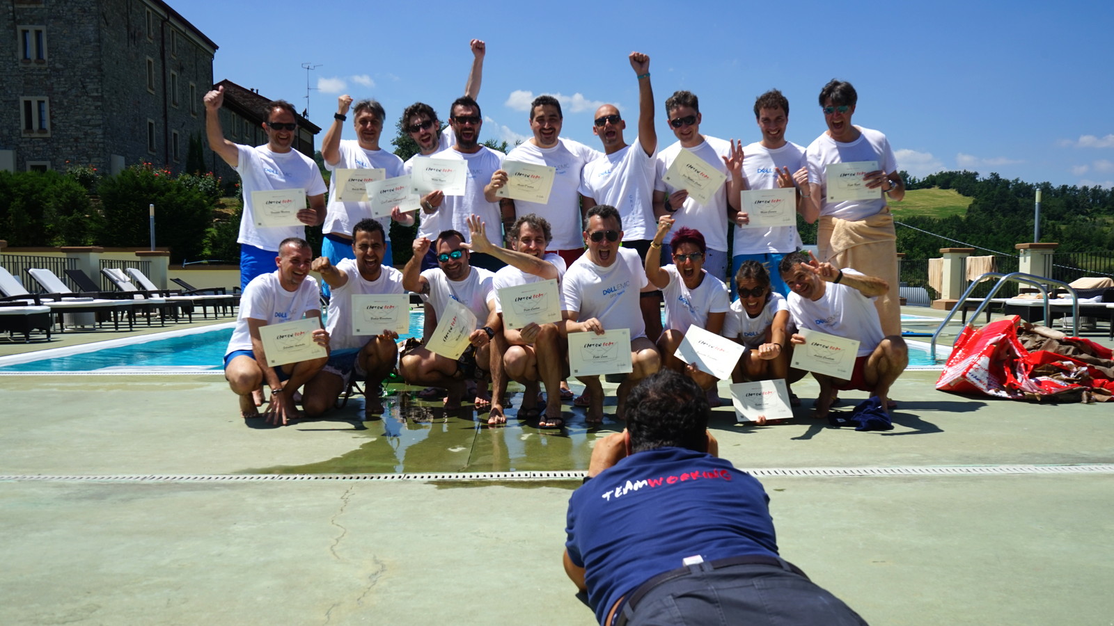 La squadra esulta a bordo piscina con gli attestati in mano, fotografata da un trainer TeamWorking