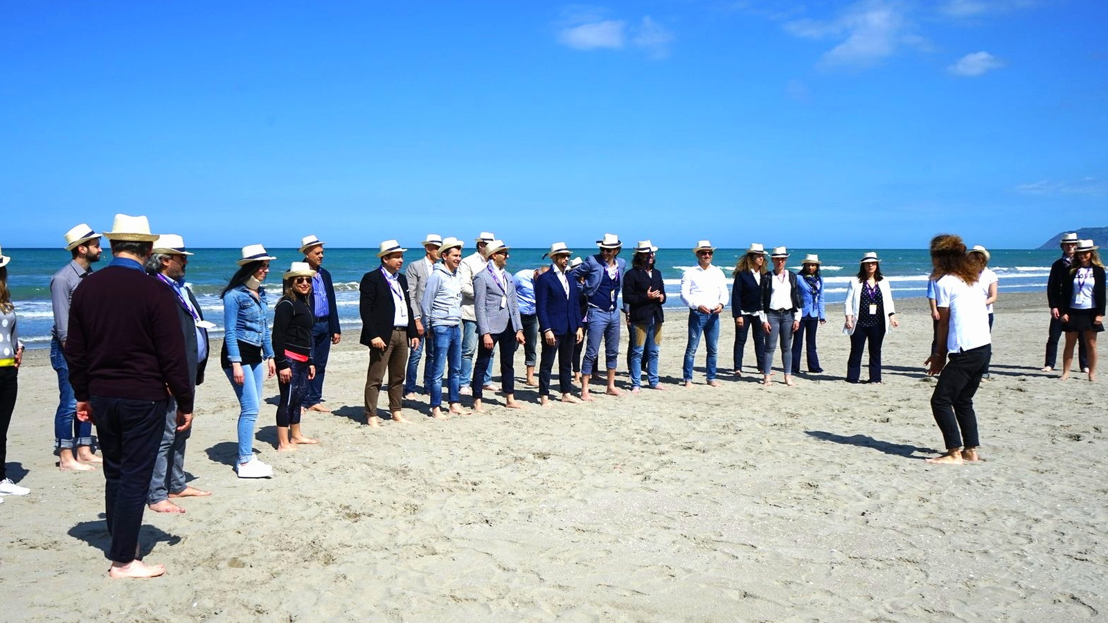 Un gruppo di partecipanti allineato sulla spiaggia guarda nella stessa direzione