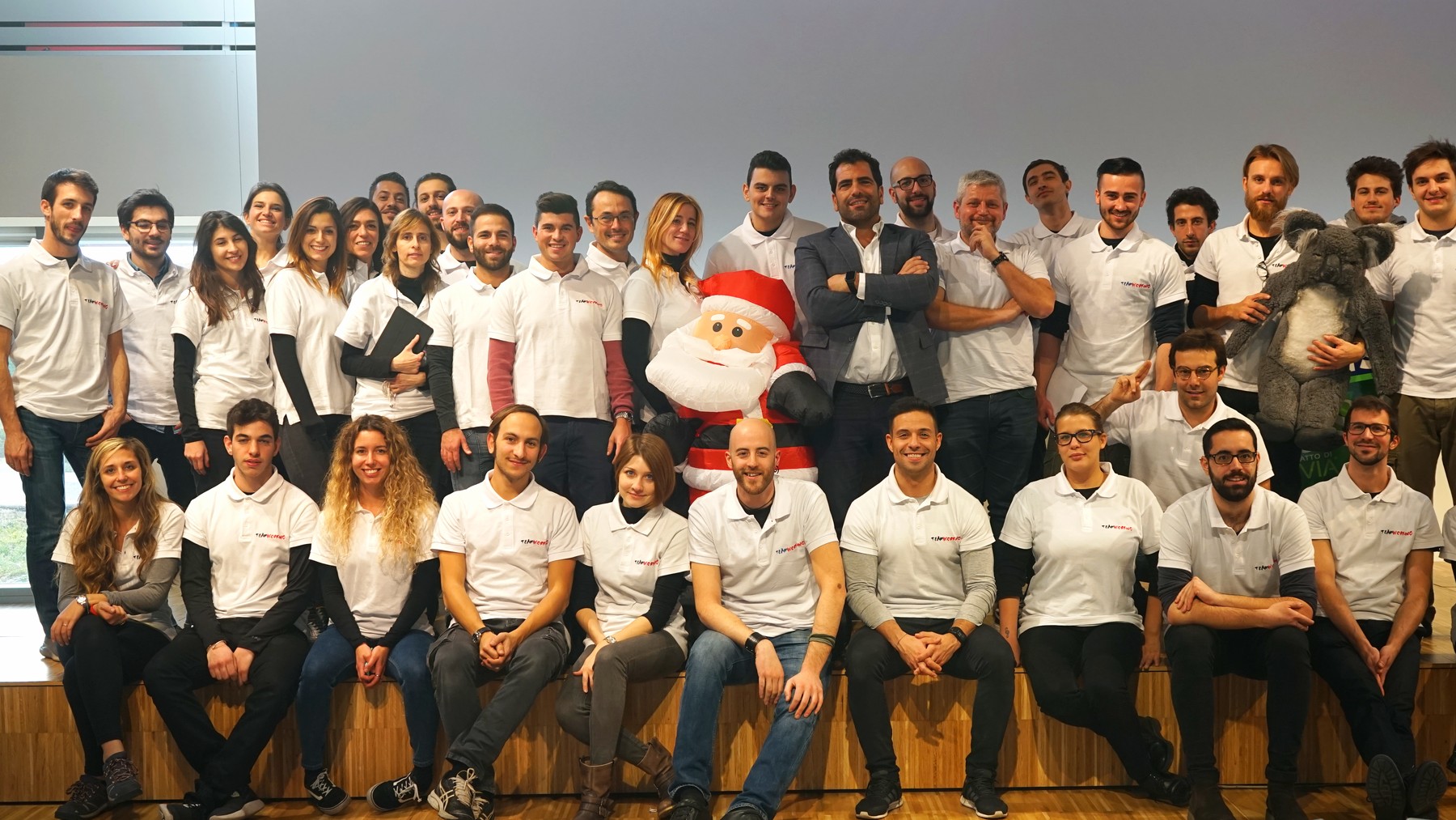 Una quarantina di trainer TeamWorking in polo bianca posano insieme su una gradinata