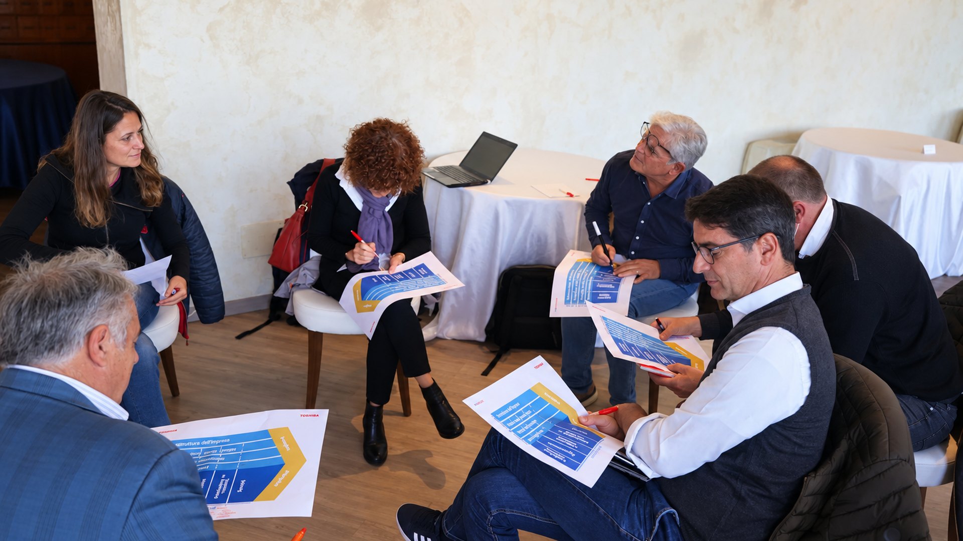 Gruppo al lavoro in cerchio sulle schede della catena del valore durante una sessione di team coaching